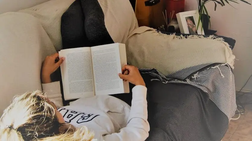 woman reading book while lying on sofa How To Get Out Of a Reading Slump