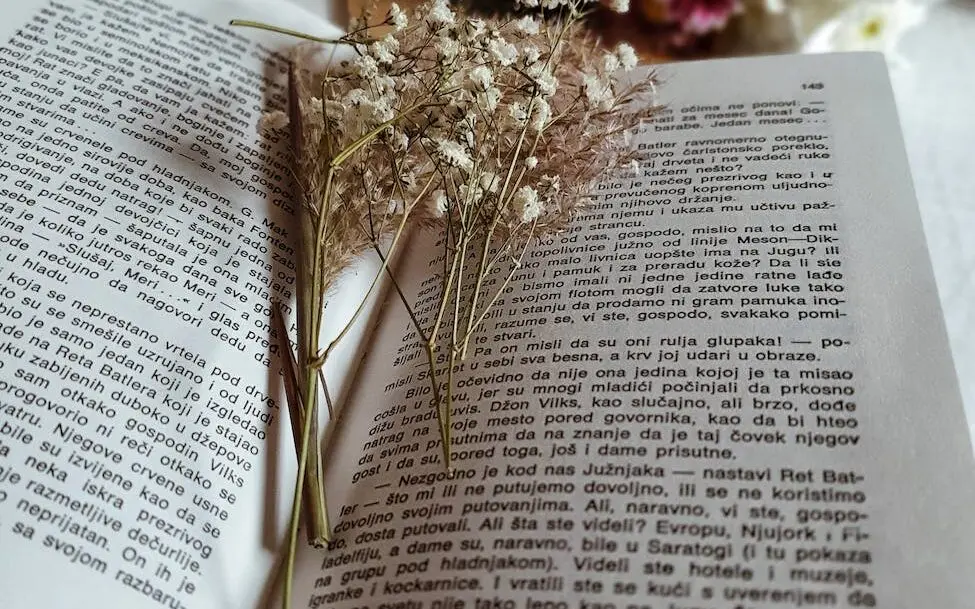 dried plants in opened book on cozy bed